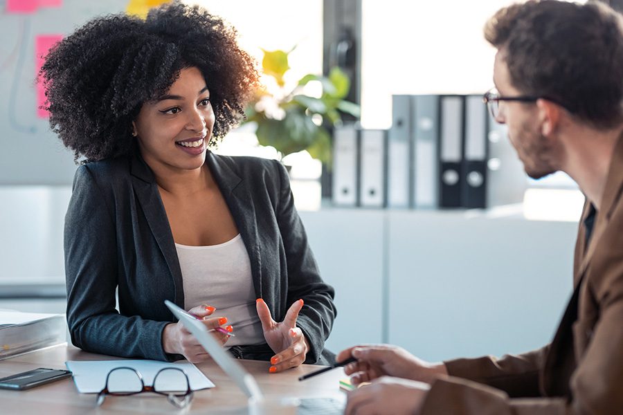 Contact - A Business Woman is Having a Discussion With a Colleague at Her Desk in an Office